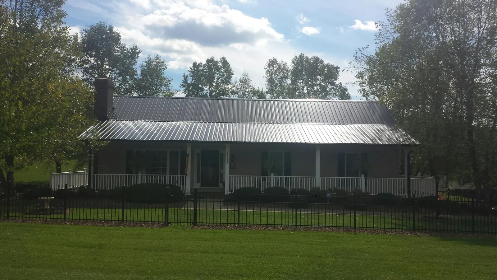 Gray metal roof on a brick ranch with a full width front porch — Gutter Guard Installation work by our crew in Hurricane
