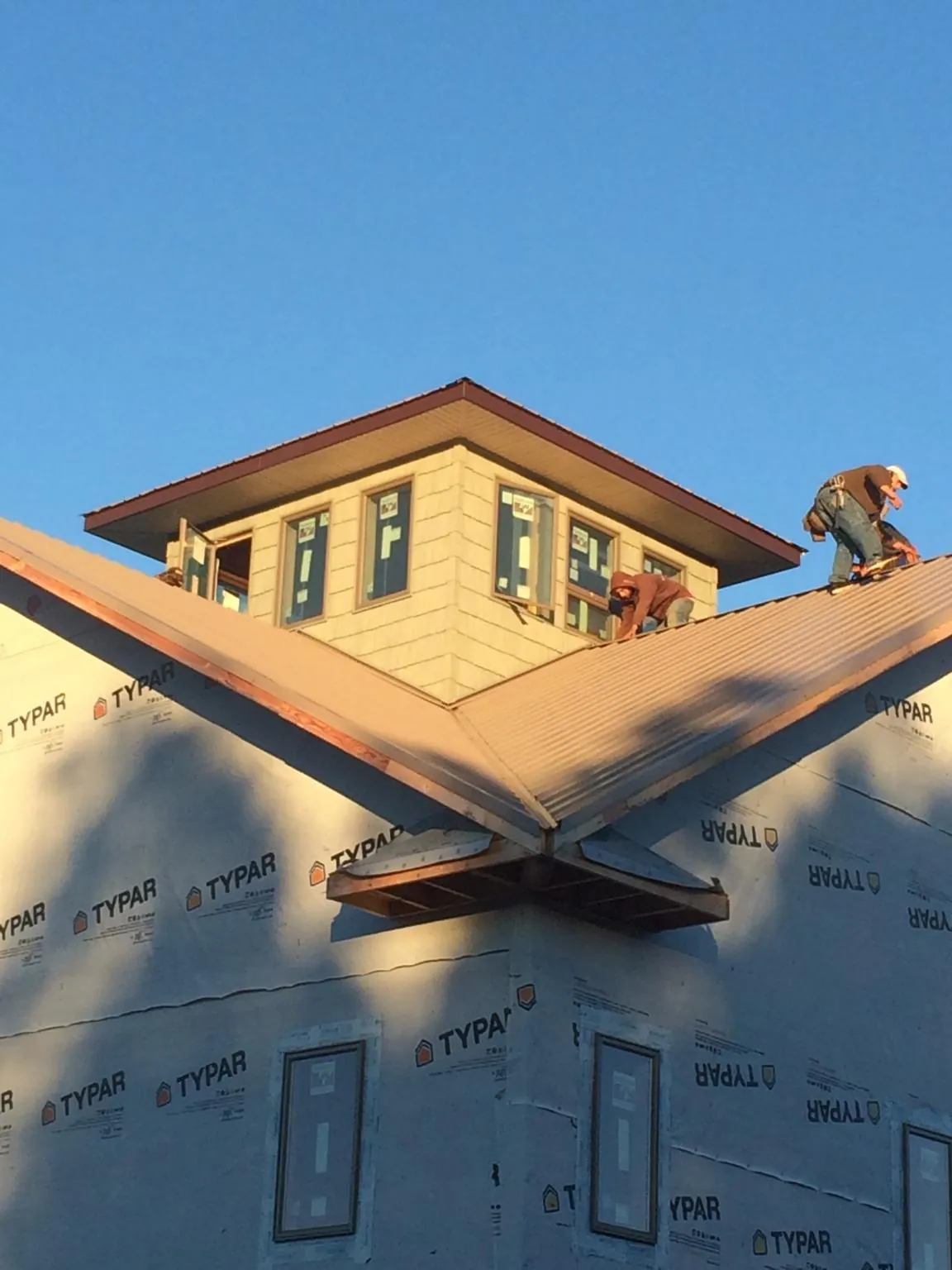 Roofers working around a rooftop cupola on a new metal roof at sunset — Roof Waterproofing in Hurricane by Roofing Brothers